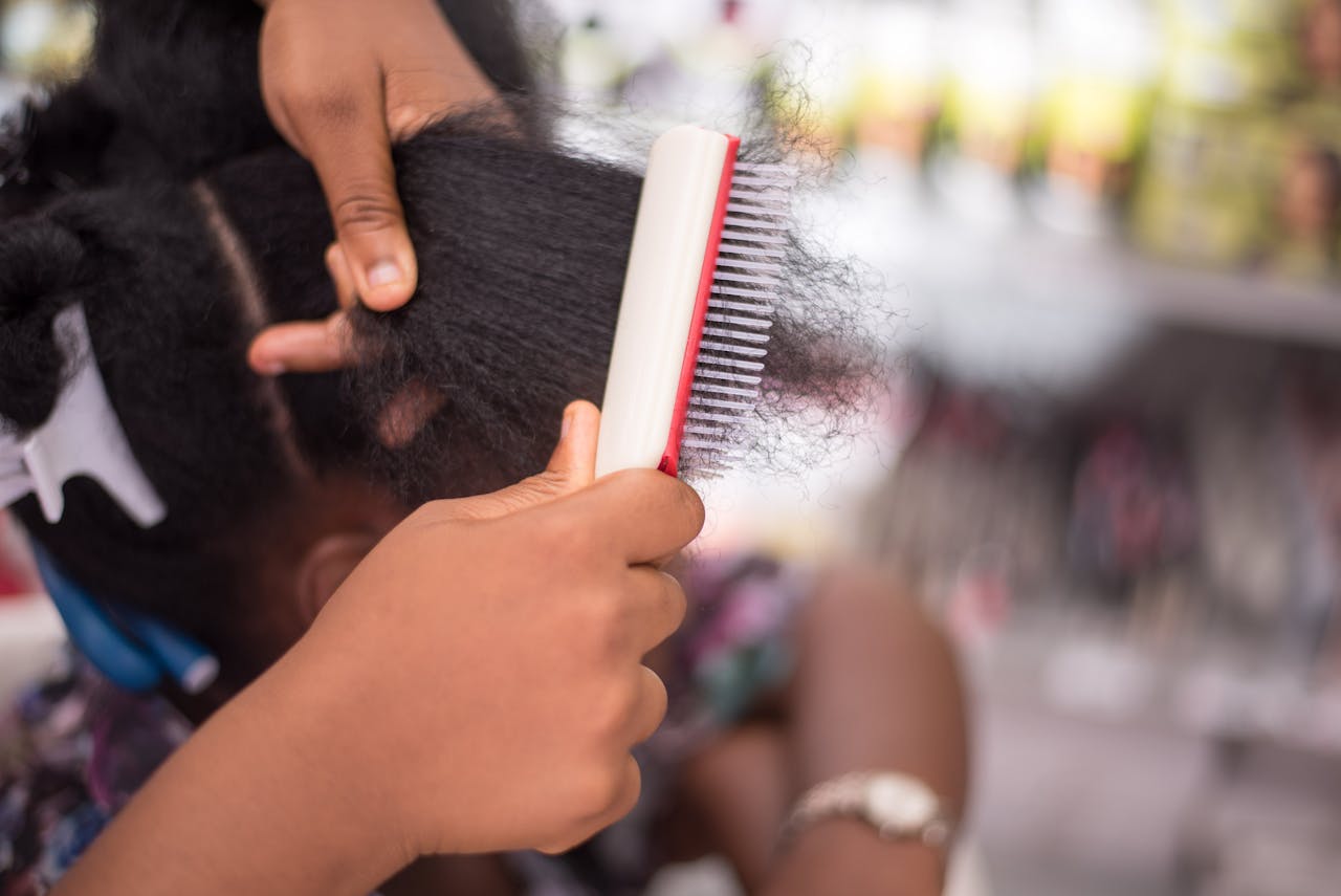 Detailed close-up of a person combing afro hair, showcasing hair care and styling techniques.
